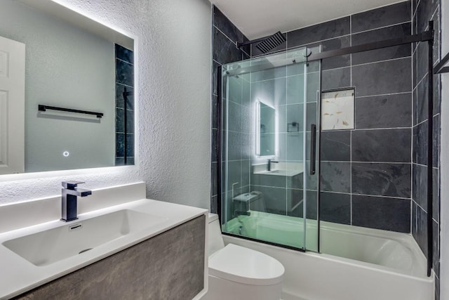 full bathroom featuring vanity, shower / bath combination with glass door, and toilet