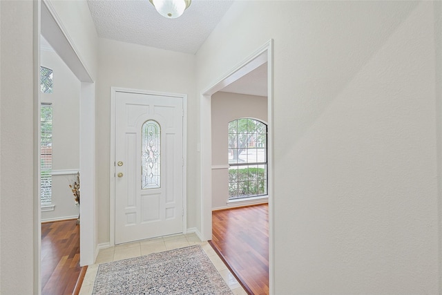 foyer entrance featuring a textured ceiling and light wood-type flooring