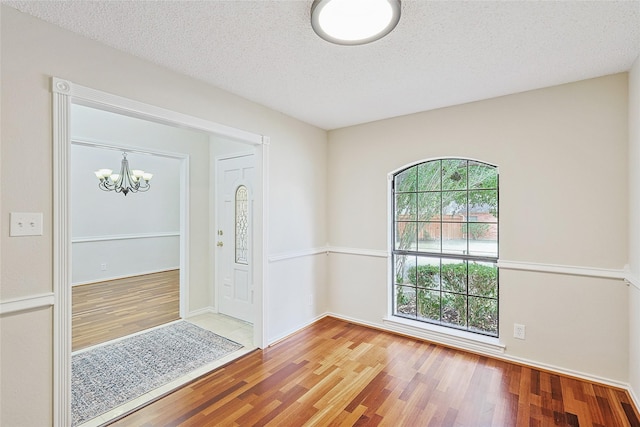 foyer with wood-type flooring, a chandelier, and a textured ceiling