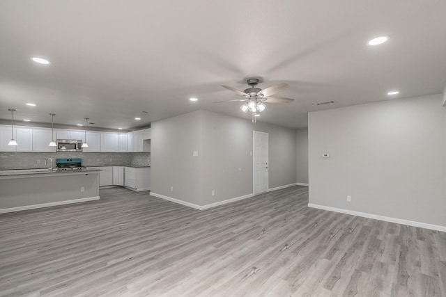 unfurnished living room with ceiling fan and light hardwood / wood-style flooring