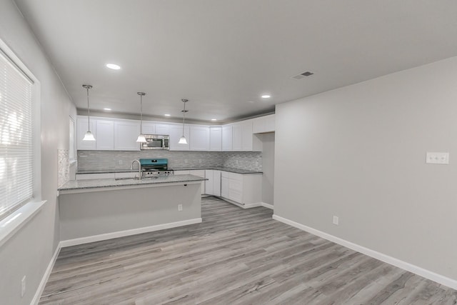 kitchen featuring sink, appliances with stainless steel finishes, light stone countertops, white cabinets, and kitchen peninsula