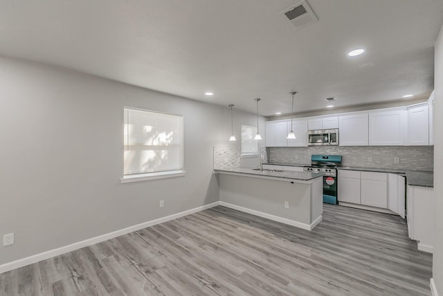 kitchen featuring white cabinetry, hanging light fixtures, appliances with stainless steel finishes, kitchen peninsula, and decorative backsplash