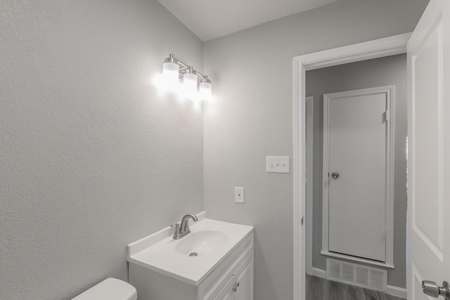 bathroom featuring vanity, hardwood / wood-style floors, and toilet