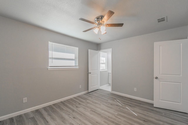 unfurnished room with a textured ceiling, ceiling fan, and light hardwood / wood-style flooring