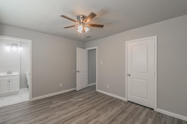 unfurnished bedroom with connected bathroom, hardwood / wood-style floors, sink, and ceiling fan