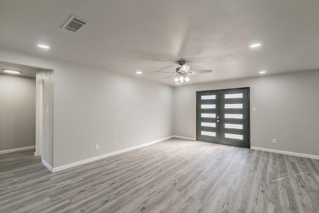 interior space featuring ceiling fan, a textured ceiling, light wood-type flooring, and french doors