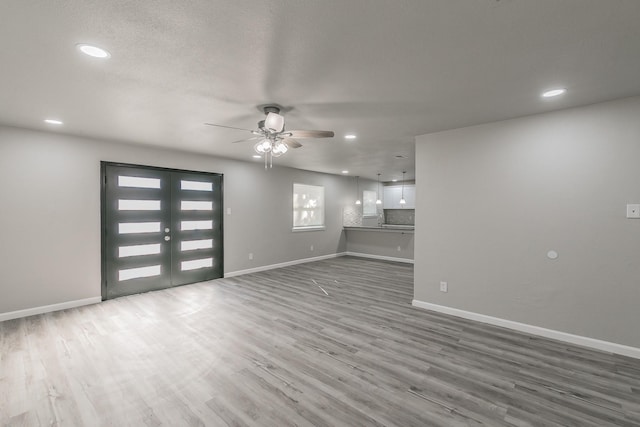 unfurnished living room with wood-type flooring, ceiling fan, and french doors