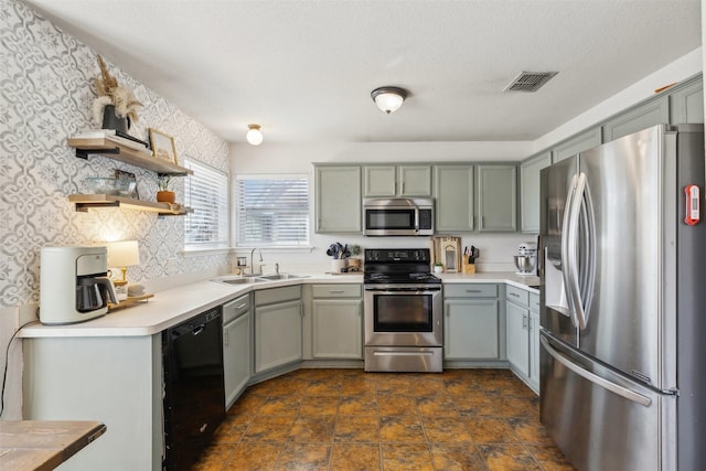 kitchen with appliances with stainless steel finishes, sink, and a textured ceiling