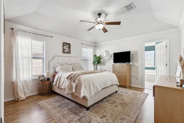 bedroom with hardwood / wood-style flooring, ornamental molding, vaulted ceiling, and multiple windows