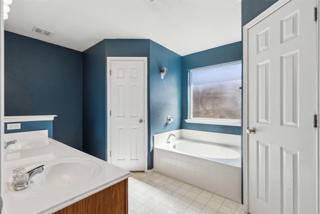 bathroom featuring tile patterned floors, vanity, and tiled bath