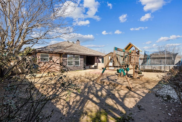 rear view of property featuring a playground and a trampoline