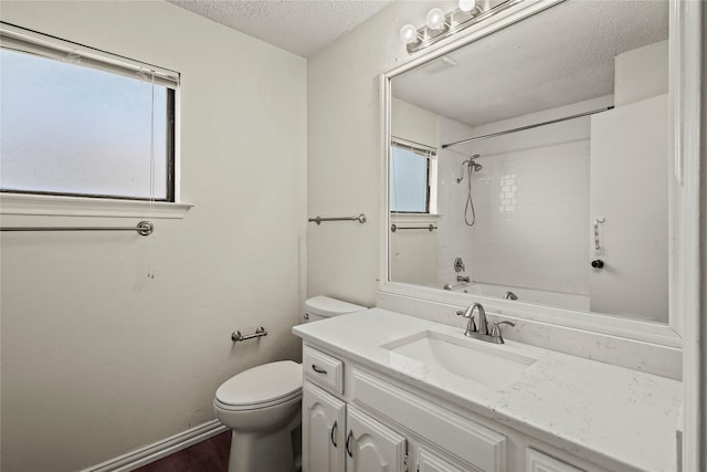 full bathroom with tiled shower / bath, vanity, toilet, and a textured ceiling