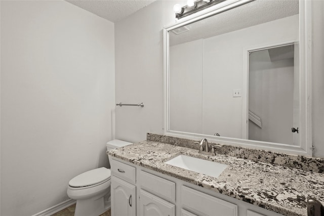 bathroom featuring vanity, toilet, and a textured ceiling