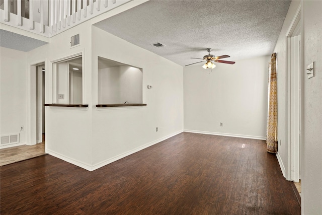 unfurnished living room featuring dark wood-type flooring, a textured ceiling, and ceiling fan