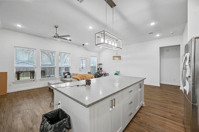 kitchen with pendant lighting, vaulted ceiling, light stone countertops, and white cabinets