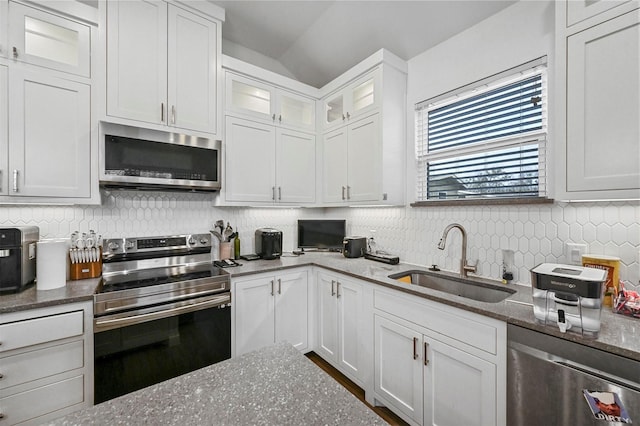 kitchen with appliances with stainless steel finishes, sink, white cabinets, and dark stone counters