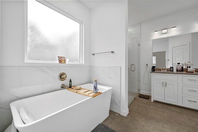 bathroom featuring tile patterned flooring, plus walk in shower, tile walls, and vanity