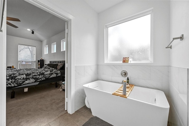 bathroom with tile walls, a bath, tile patterned floors, and ceiling fan