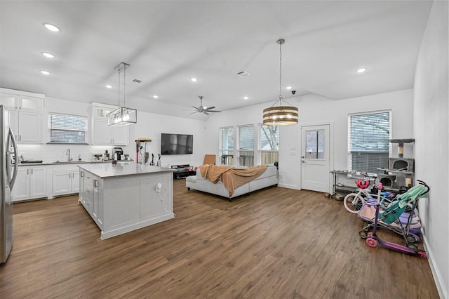 kitchen with sink, white cabinetry, dark hardwood / wood-style flooring, a kitchen island, and pendant lighting