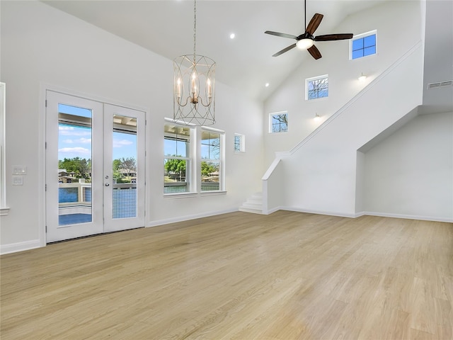 unfurnished living room featuring a high ceiling, a healthy amount of sunlight, light hardwood / wood-style floors, and french doors