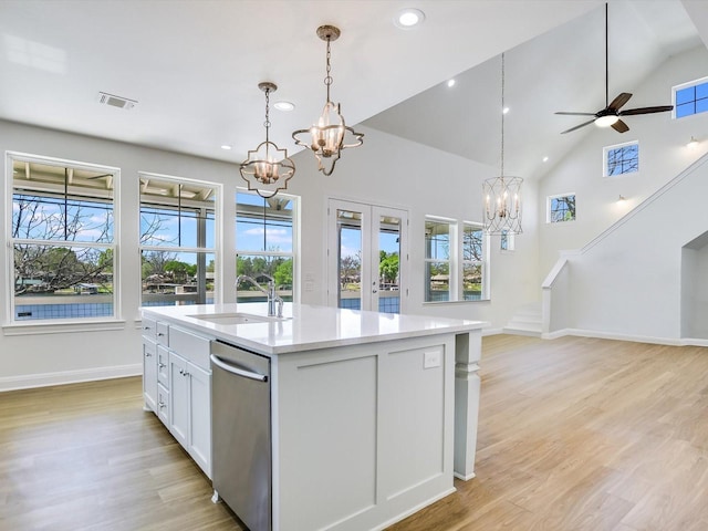 kitchen with decorative light fixtures, white cabinetry, sink, a kitchen island with sink, and stainless steel dishwasher