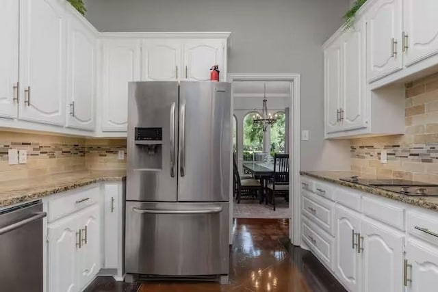 kitchen with tasteful backsplash, appliances with stainless steel finishes, white cabinets, and light stone counters