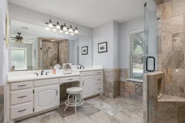 bathroom with vanity, tile walls, ceiling fan, and a shower with shower door