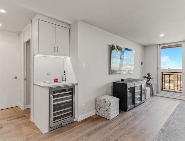 bar featuring white cabinetry, beverage cooler, and light wood-type flooring