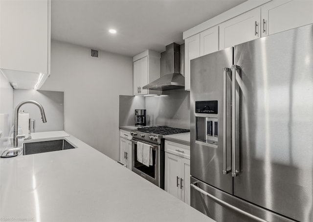 kitchen featuring white cabinetry, wall chimney range hood, sink, and appliances with stainless steel finishes