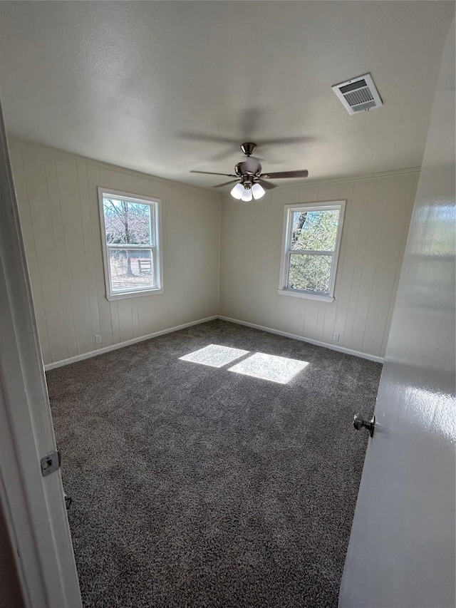 unfurnished room featuring ceiling fan, a healthy amount of sunlight, and dark carpet