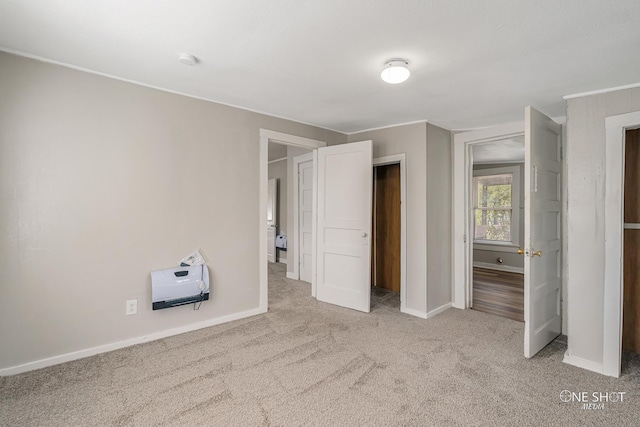 unfurnished bedroom featuring heating unit and light colored carpet