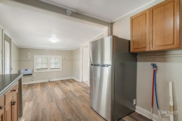 kitchen featuring heating unit, crown molding, stainless steel fridge, and light hardwood / wood-style floors