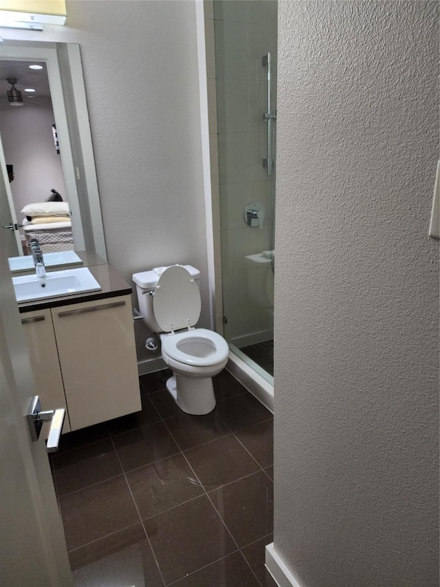 bathroom featuring vanity, toilet, tile patterned flooring, and a shower with door