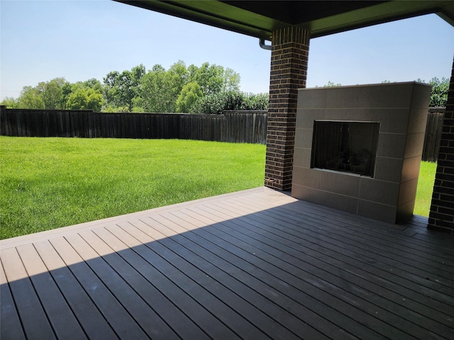 deck with an outdoor brick fireplace and a lawn