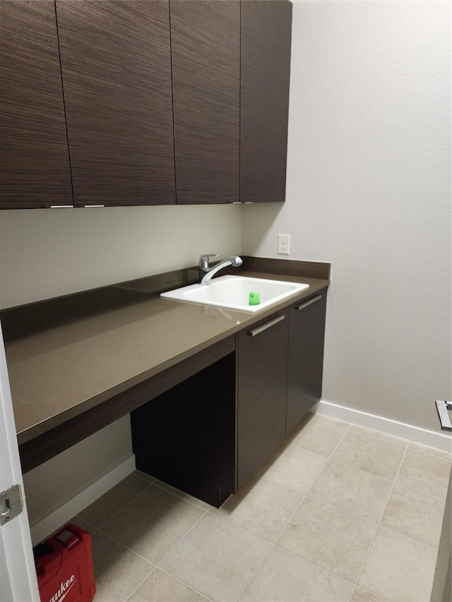 clothes washing area with sink, cabinets, and light tile patterned flooring