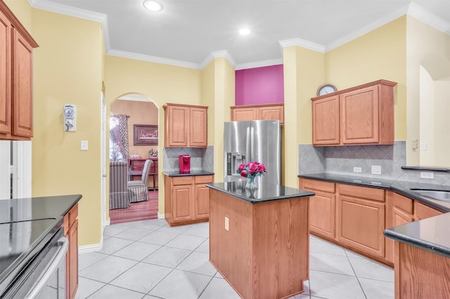 kitchen featuring light tile patterned floors, stainless steel fridge, backsplash, a center island, and ornamental molding