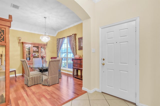 dining area featuring crown molding, light hardwood / wood-style floors, and a notable chandelier