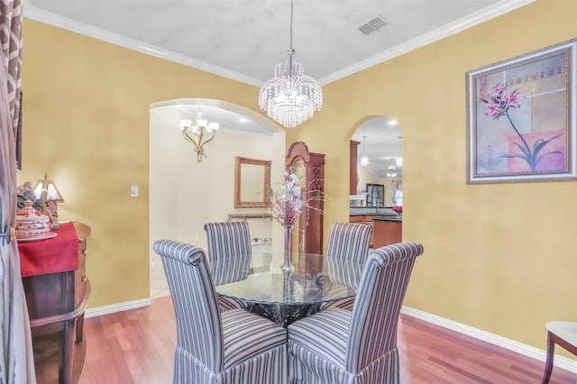 dining area featuring hardwood / wood-style flooring, crown molding, and a notable chandelier