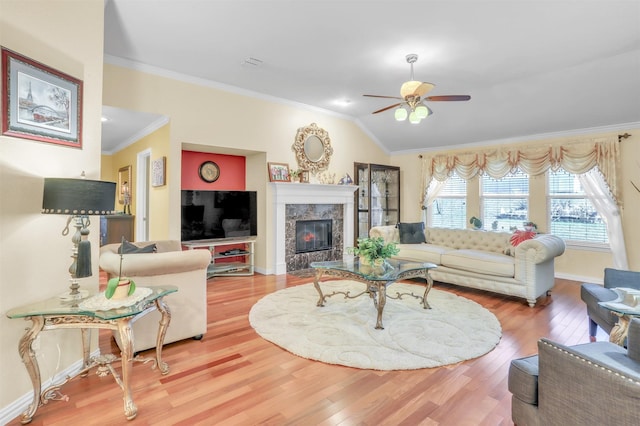 living room with vaulted ceiling, ornamental molding, ceiling fan, a fireplace, and hardwood / wood-style floors