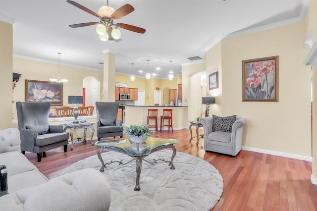 living room featuring ornamental molding, ceiling fan with notable chandelier, and light hardwood / wood-style flooring