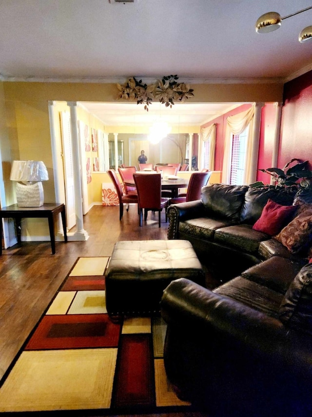 living room featuring crown molding, decorative columns, and light wood-type flooring