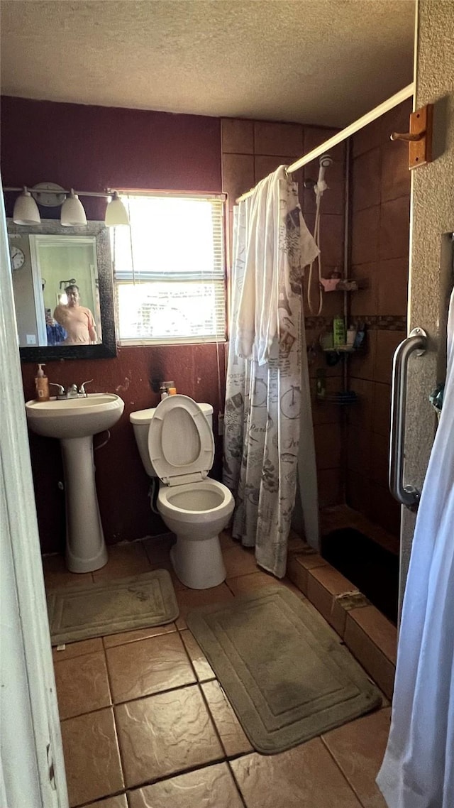 bathroom featuring walk in shower, toilet, sink, and a textured ceiling