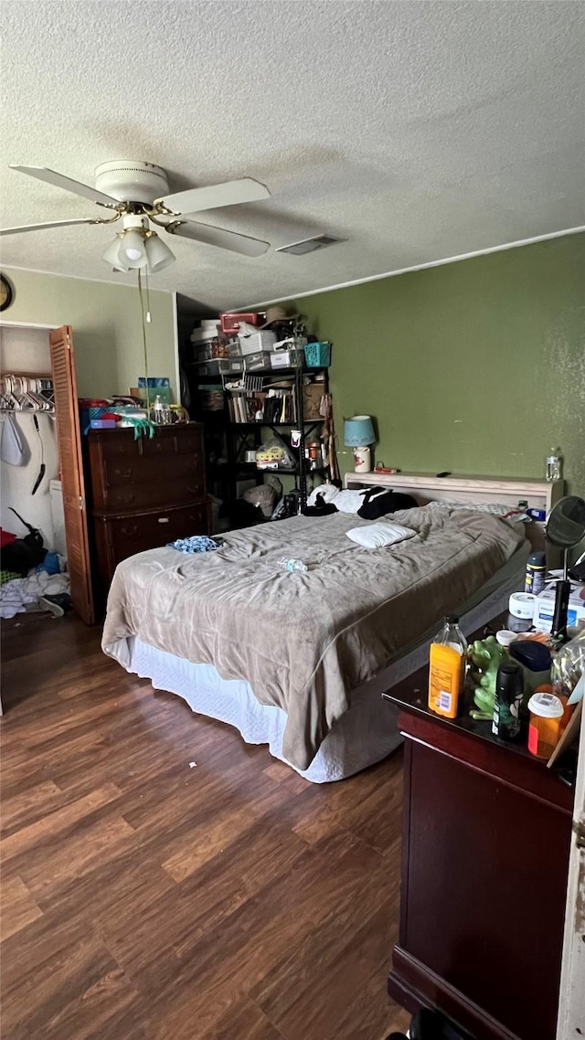 bedroom featuring ceiling fan, dark hardwood / wood-style floors, and a textured ceiling