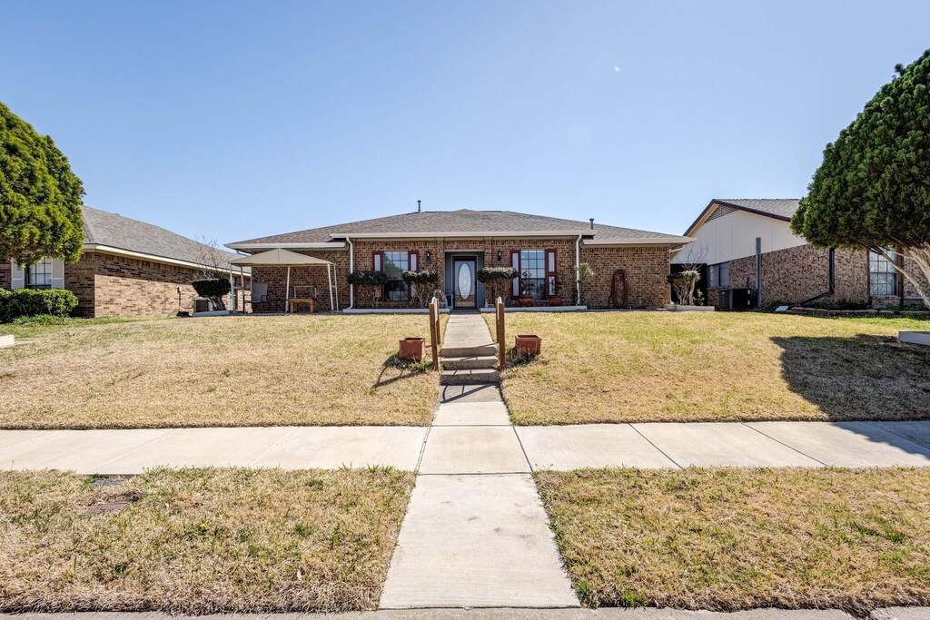 rear view of house with central AC and a lawn