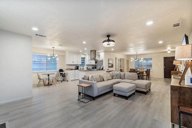 living room featuring plenty of natural light, light hardwood / wood-style floors, and a chandelier