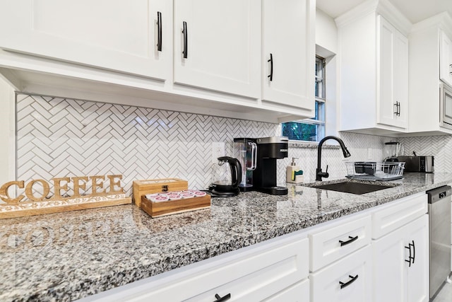 kitchen with stainless steel dishwasher, light stone countertops, sink, and white cabinets