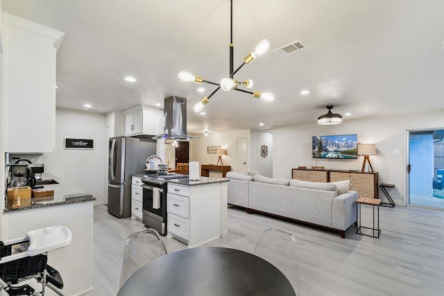 kitchen featuring white cabinetry, dark stone countertops, stainless steel appliances, island exhaust hood, and decorative light fixtures