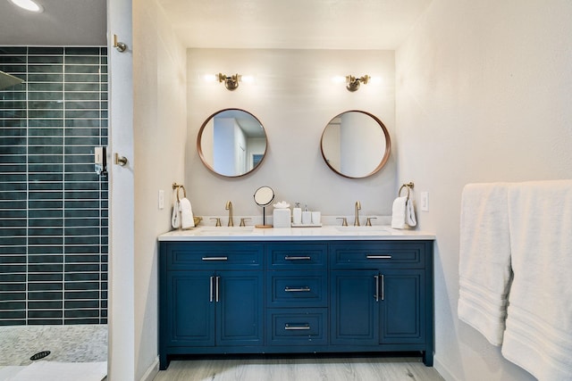 bathroom featuring hardwood / wood-style floors, vanity, and a tile shower