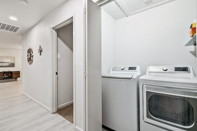 washroom with washer and dryer and light hardwood / wood-style flooring