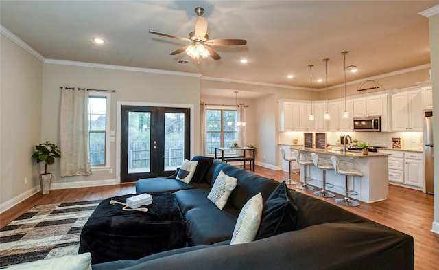 living room featuring french doors, crown molding, and light hardwood / wood-style floors